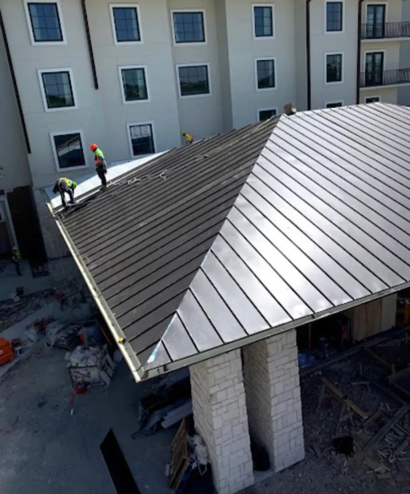 Crew installing standing seam metal roof panels on a commercial project in East Windsor